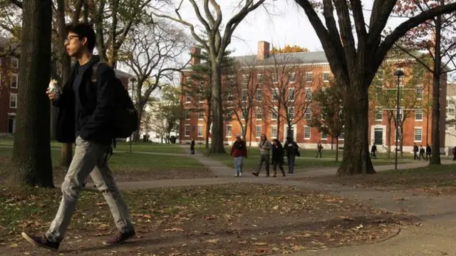 Estudiante caminando en un parque en el campus de Harvard