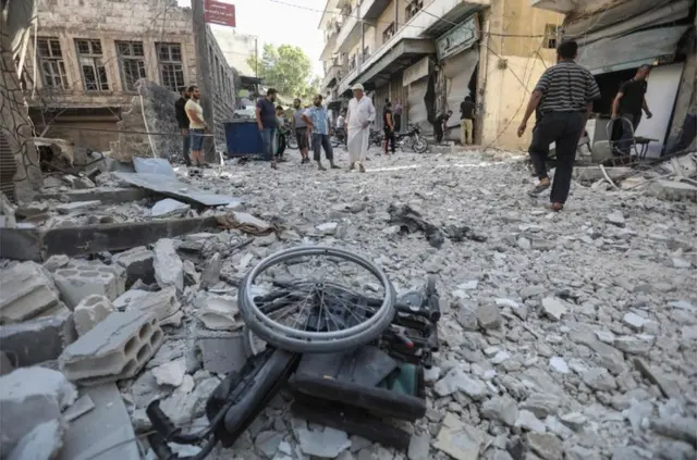 Uma cadeira de rodas em meio aos escombros dos edifícios destruídos em Ariha
