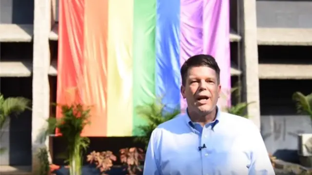 Balozi mdogo wa Marekani katika mji wa Chennai Robert Burgess akiwa mbele ya jengo la ofisi yake ya ubalozi ulio na bendera wapenzi jinsia moja