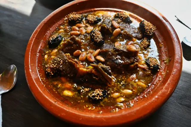 طبق من اللحم بالبرقوق مزين بالسمسم واللوز