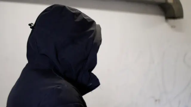 фотографија непознате особе која има црну јакну и капуљачу на глави