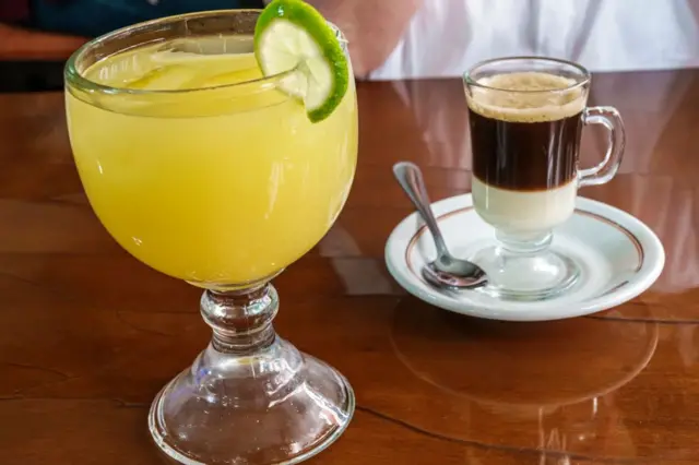 Uma xícara de café e um copo de suco em cima de uma mesa 