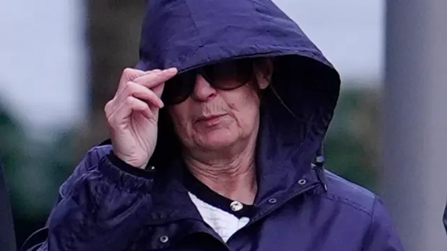 Joanne Sharkey, vestindo um casaco azul com o capuz puxado sobre o cabelo e grandes óculos de sol, do lado de fora do tribunal em Liverpool