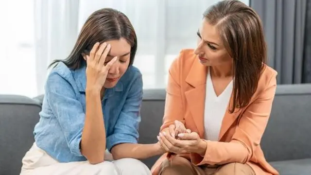 امرأة تمسك بيد فتاةز والفتاة تضع يدها الثانية على وجهها ويبدو عليها التوتر والقلق