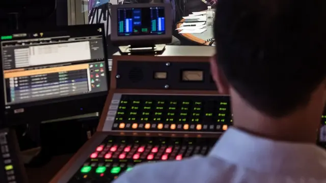 A radio studio sound desk viewed from behind a producer