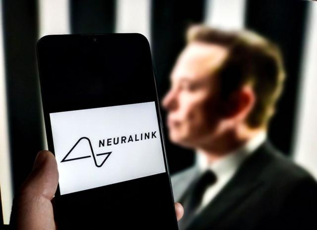 Teléfono mostrando un logo de Neuralink con Elon Musk en el fondo. 
