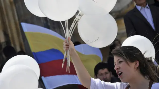 Mujer con globos blancos y bandera de Colombia