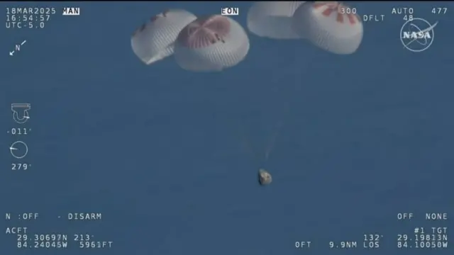 Cápsula con los astronautas cayendo con 4 paracaídas.