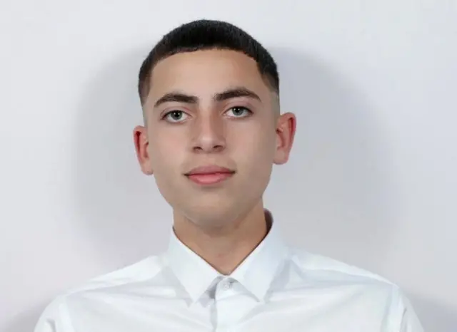 Подросток в белой рубашке смотрит прямо в камеру