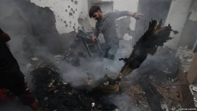 चकमकीनंतर घराबाहेरचा मलबा हटविणारा तरुण