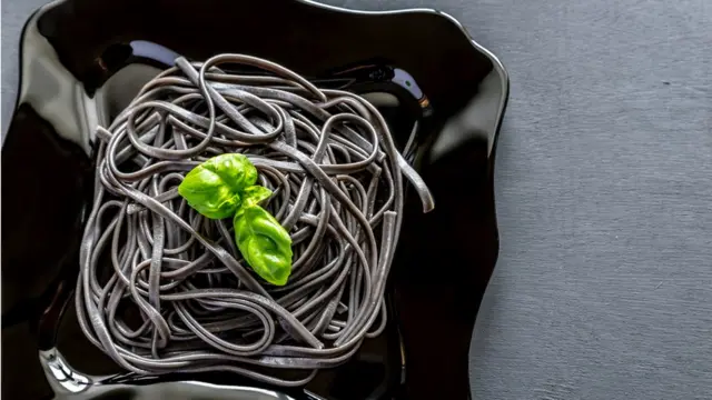 Черные лингуини с листком базилика