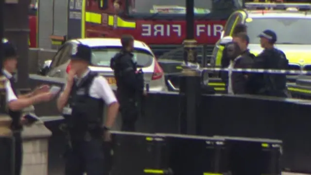 المشتبه به (على يمين الصورة) في قبضة الشرطة، التي تصطحبه بعيدا عن المكان