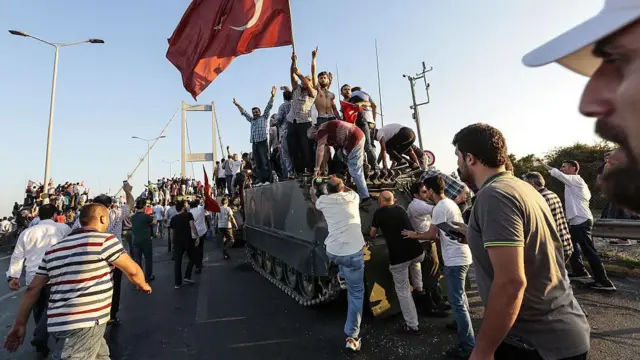 Recep Tayyip Erdogan elnök támogatói török zászlókat lengetnek, miközben elfoglalnak egy harckocsit, miután a puccskísérletben részt vevő katonák megadták magukat Isztambul Boszporusz hídján.