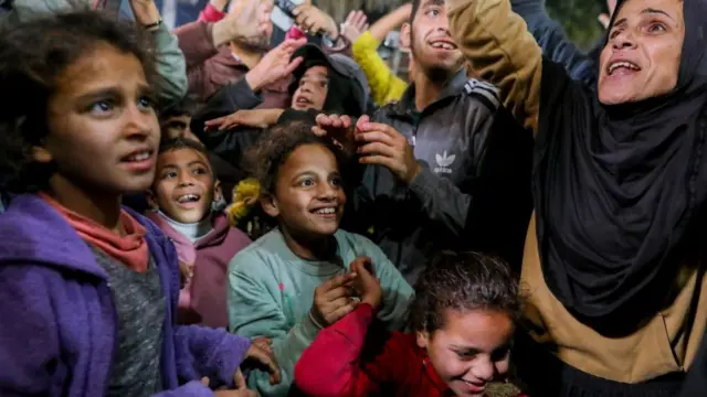 Adultos e crianças sorrindo e levantando os braços em comemoração