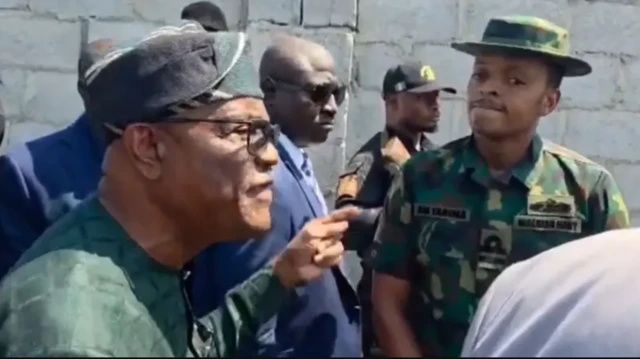 Nyesom Wike ń woju ọmọ ológun to wa ninu aṣọ ológun tí tíì ṣe aláwọ̀ èwe. Ọ̀pọ̀ èèyàn yí àwọn méjèèjì ká.