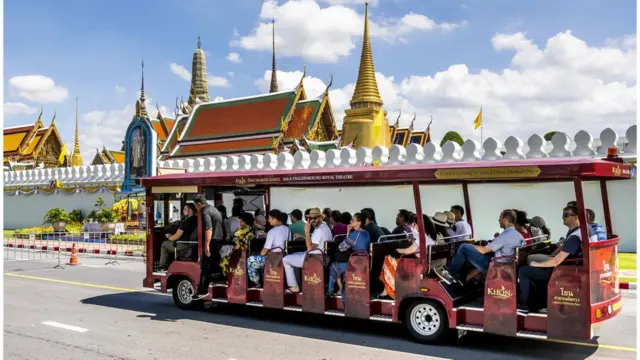 Tourists ride a bus in front of the Thai Royal Palace in Bangkok on September 12, 2019.