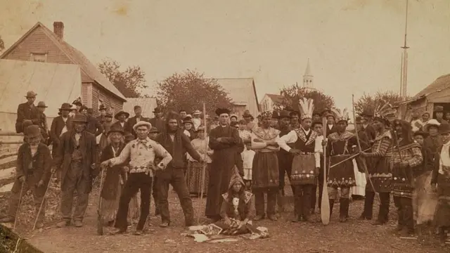 Un religioso ruso y colonos rusos posan para la foto junto a pobladores nativos vestidos con trajes tradicionales en la ciudad de Sitka, en Alaska, en torno a 1900. (Foto de Michael Maslan/Corbis/VCG vía Getty Images)