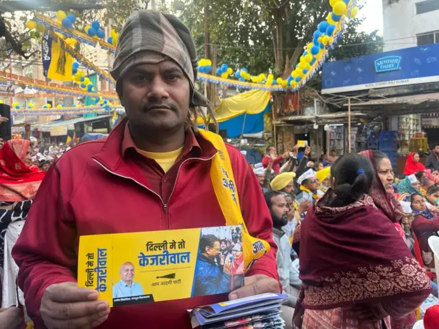 बचत कार्ड दिखाता शख़्स