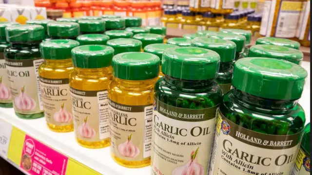 Yellow and green bottles wey contain garlic oil and garlic extract capsules on a shelf