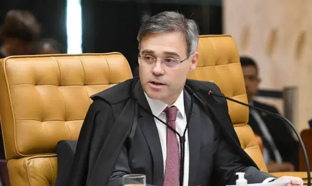 André Mendonça veste terno e toga, sentado em uma cadeira no plenário do Supremo Tribunal Federal