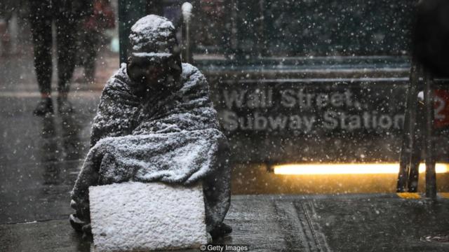 Imagem mostra possível morador de rua sentado em meio à nevasca