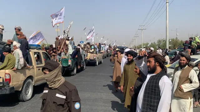 خیابانی در قندهار که مردم رژه نیروهای طالبان را تماشا می‌کنند