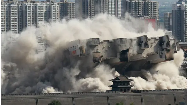 8月8日，山西大同，當地政府對位於北城牆武定西門外的一座90米高的大樓實施爆破拆除，飛揚的塵土與古城牆呼應形成壯觀場面。