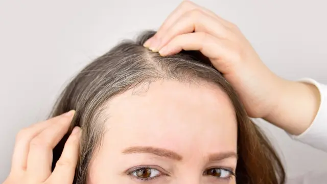 Mulher com cabelos mexendo em seus cabelos brancos