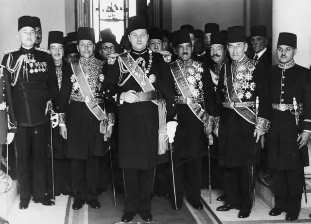 الملك فاروق بالزي العسكري وسط حاشيته.