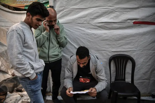 فلسطینیان خان یونس در حال خواندن اعلامیه هشدار اسرائیل در مورد عملیات در آن منطقه