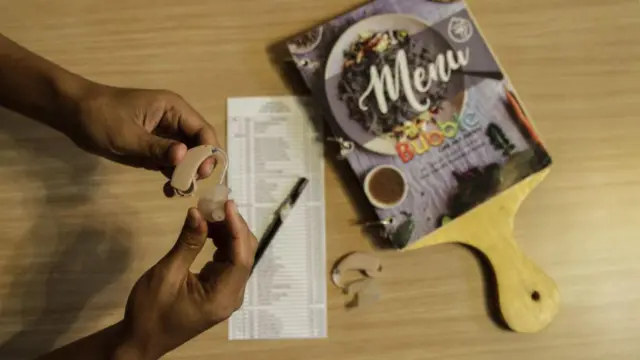 Seorang tuna rungu memegang alat bantu dengar.