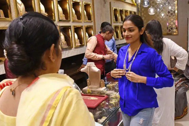 Seorang wanita mencoba kalung emas di toko Senco Gold and Diamonds pada kesempatan Dhanteras di Mumbai.