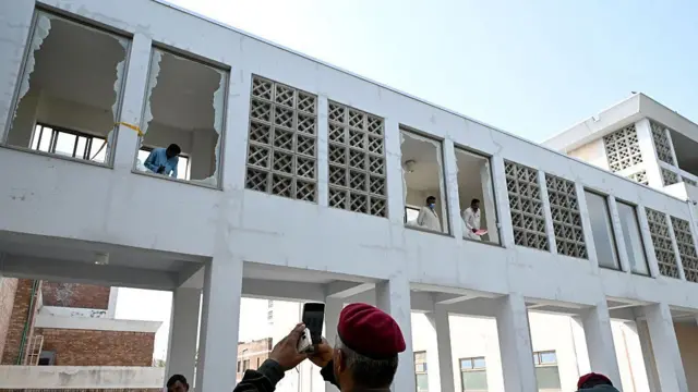 İşçiler, İslamabad'daki Pakistan Tıp Bilimleri Enstitüsü (PIMS) Hastanesi'nin Anne ve Çocuk Sağlığı (MCH) servisi dışında çıkan yangının ardından kırılan cam parçalarını temizliyor.