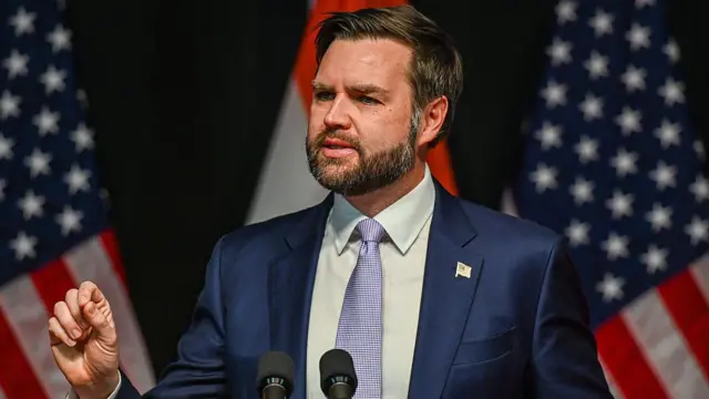 El vicepresidente JD Vance durante un discurso y con bandera de Estados Unidos detrás de él.