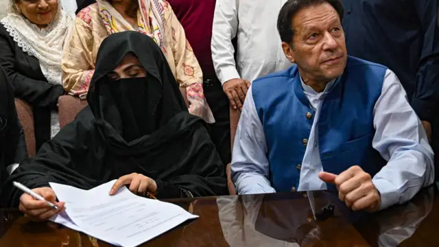 Pakistan's former Prime Minister, Imran Khan along with his wife Bushra Bibi looks on as he signs surety bonds for bail in various cases, at a registrar office in the High court.