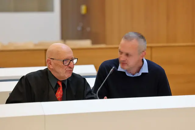 Александр Й. (спрва) сидит рядом с адвокатом Йоргеном Э. Леске (слева) перед началом заседания.