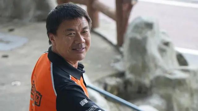 身穿橙色Polo恤的王计兵面带笑容望向镜头。
