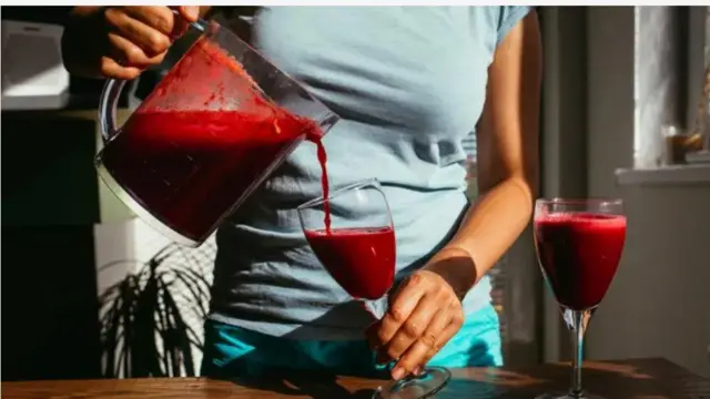 Aworan ẹni to n da omi eso beetroot sinu ife