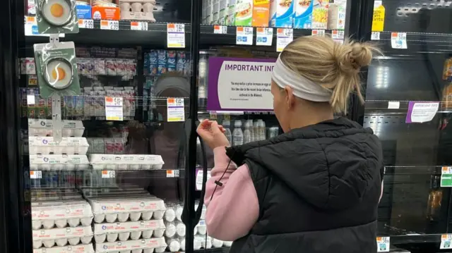 वर्जीनिया में एक महिला बिक्री के लिए रखे अंडों की कीमतें देख रही हैं