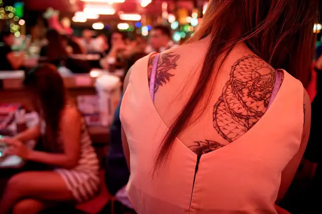PATTAYA, THAILAND - 2013/02/20: A young Thai-woman sits inside a red-light bar as she waits for a customer to resolve the bar fee to take her home for the night. With its reputation as one of the epicenters of Thailand's sex industry, Pattaya .
