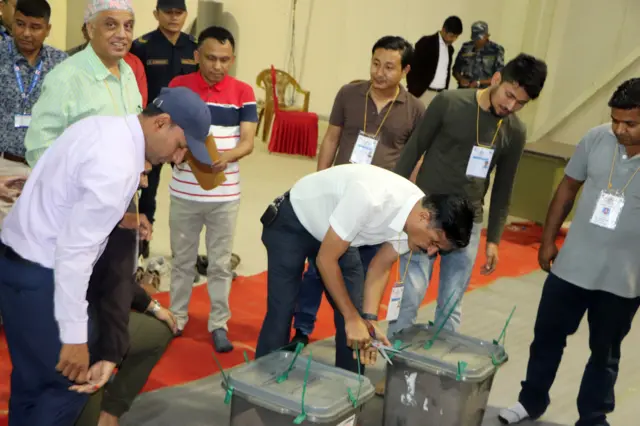 मतपेटिका खोल्दै कर्मचारी