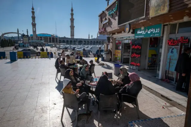 چند زند در بیرون یم سانودیچ‌فروشی پشت میز نشسته‌اند