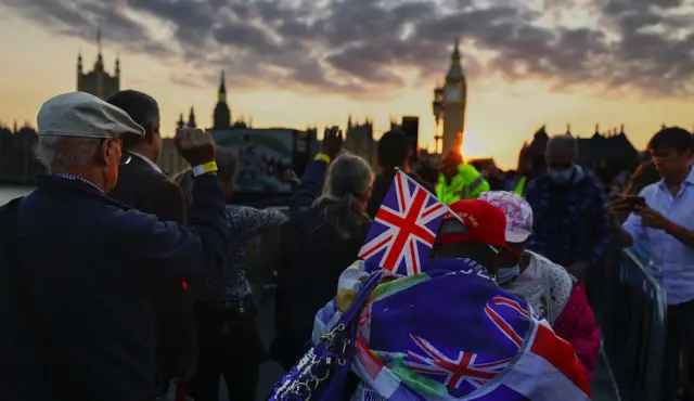 議會大廈前舉著國旗的排隊男子