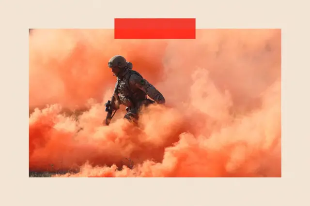 Brytyjski żołnierz w chmurze pomarańczowego dymu podczas symulowanego ataku. 