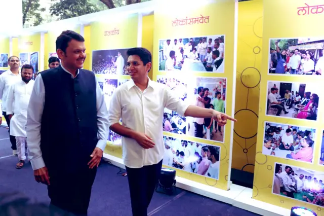 सत्यजित तांबे, देवेंद्र फडणवीस प्रदर्शनातील फोटो पाहाताना