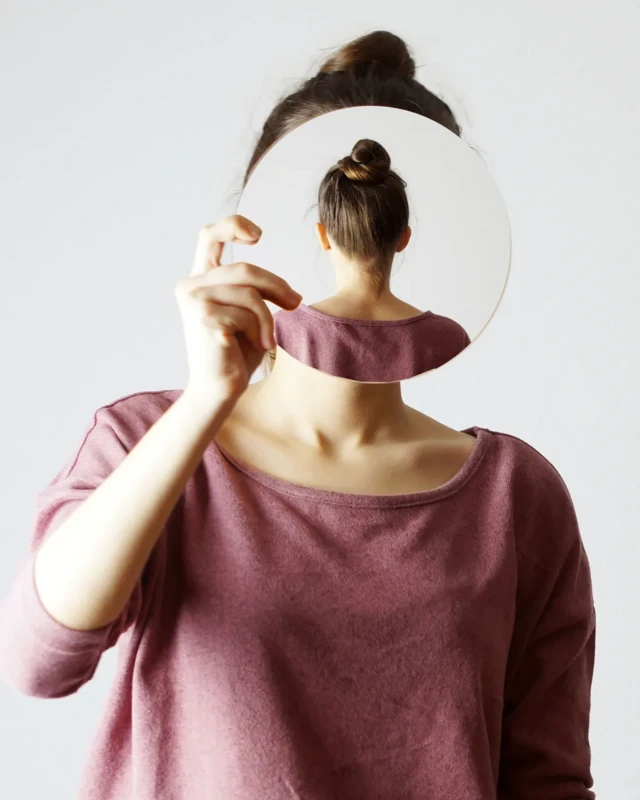 زنی قابی جلوی چهرهاش گرفته که در پشت قاب، تصویری از پشت زن دیده میشود