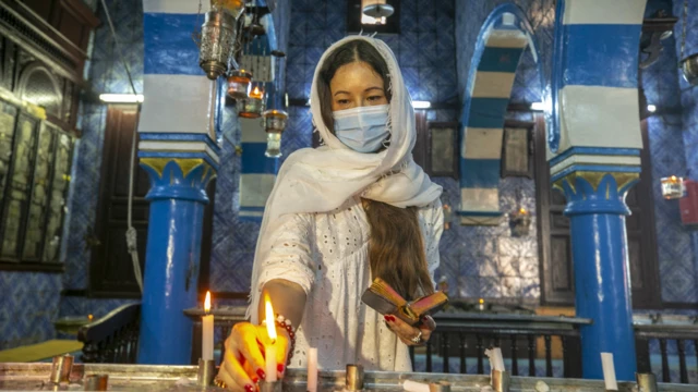 Nan kuma wata Bayahudiya ce ta kunna kyandir a wurin ibada ta Ghriba a tsibirin Djerba da ke Tunisia ranar Juma'a...