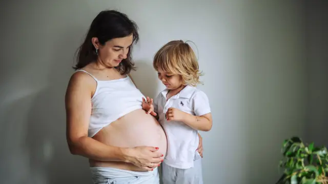 Mulher grávida ao lado de uma criança já mais velha