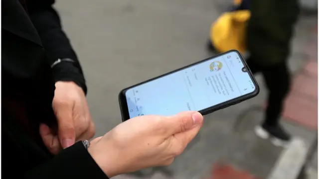فتاة إيرانية تحمل هاتفا يوضح عدم تمكنه من الاتصال بالإنترنت