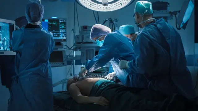 Médicos em uma sala de cirurgia utilizando um desfibrilador.